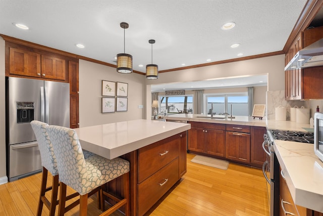 kitchen featuring crown molding, light wood-style flooring, a breakfast bar, and appliances with stainless steel finishes