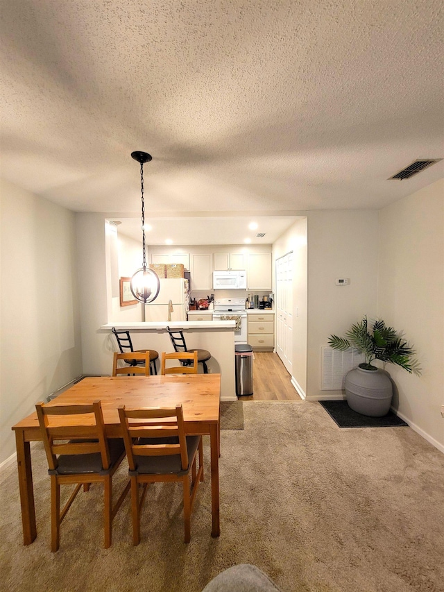 carpeted dining room with a textured ceiling