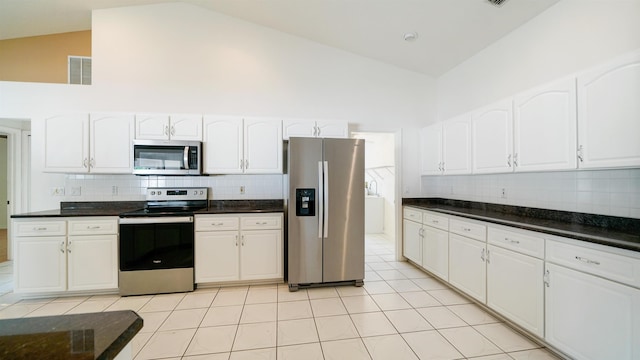 53 Pritchard Dr, Palm Coast, FL 32164 - kitchen with stainless steel appliances, high vaulted ceiling, white cabinets, backsplash, and light tile patterned flooring