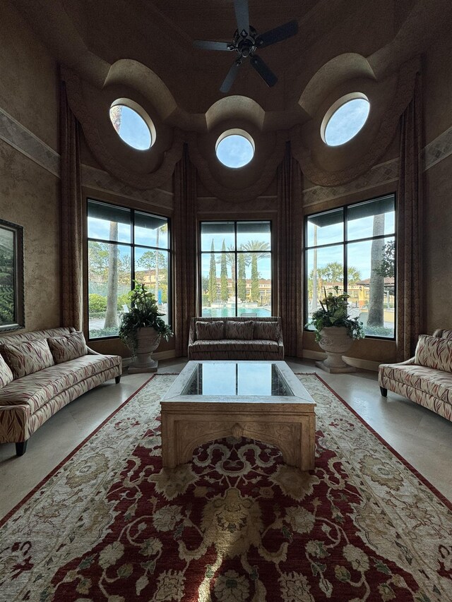 living room featuring ceiling fan, a wealth of natural light, and a high ceiling