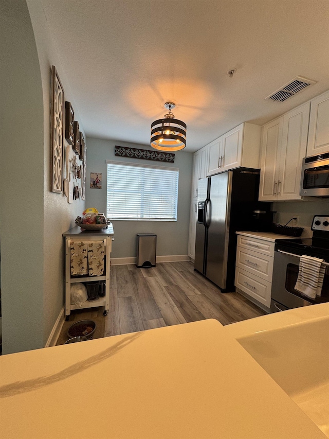 kitchen featuring light hardwood / wood-style flooring, stainless steel appliances, and white cabinets