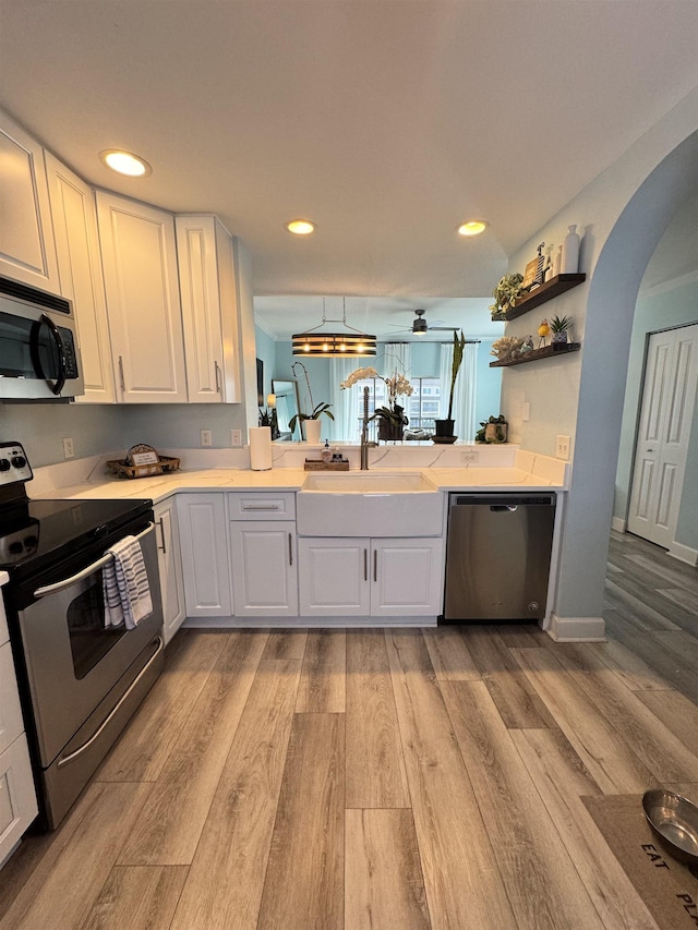 kitchen featuring appliances with stainless steel finishes, white cabinetry, sink, ceiling fan, and light wood-type flooring