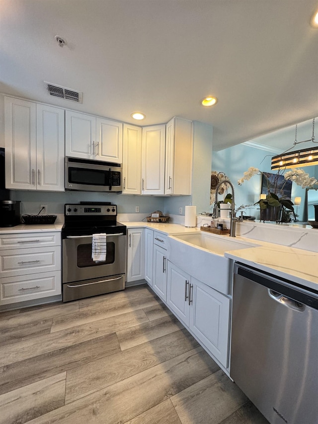 kitchen featuring appliances with stainless steel finishes, white cabinets, and light hardwood / wood-style floors