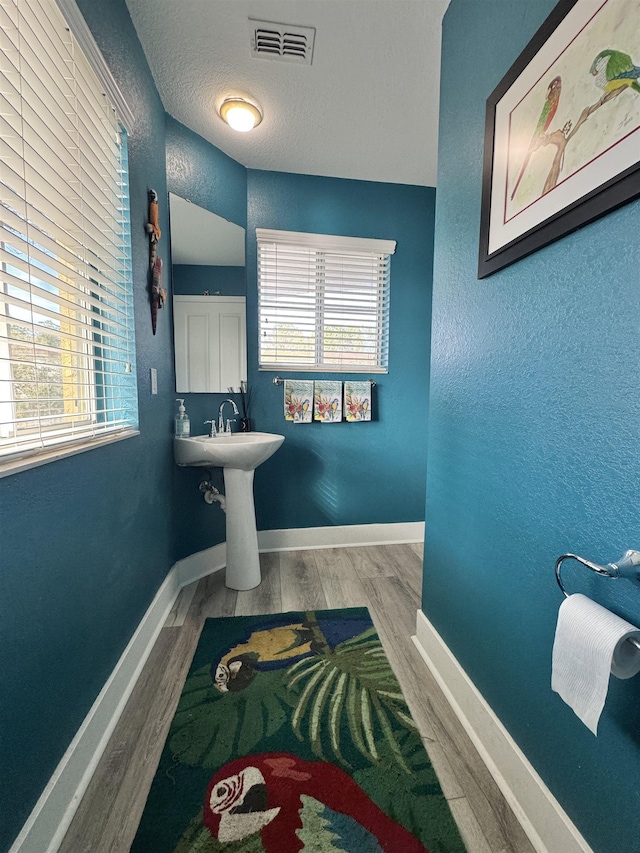 bathroom with hardwood / wood-style flooring and a textured ceiling