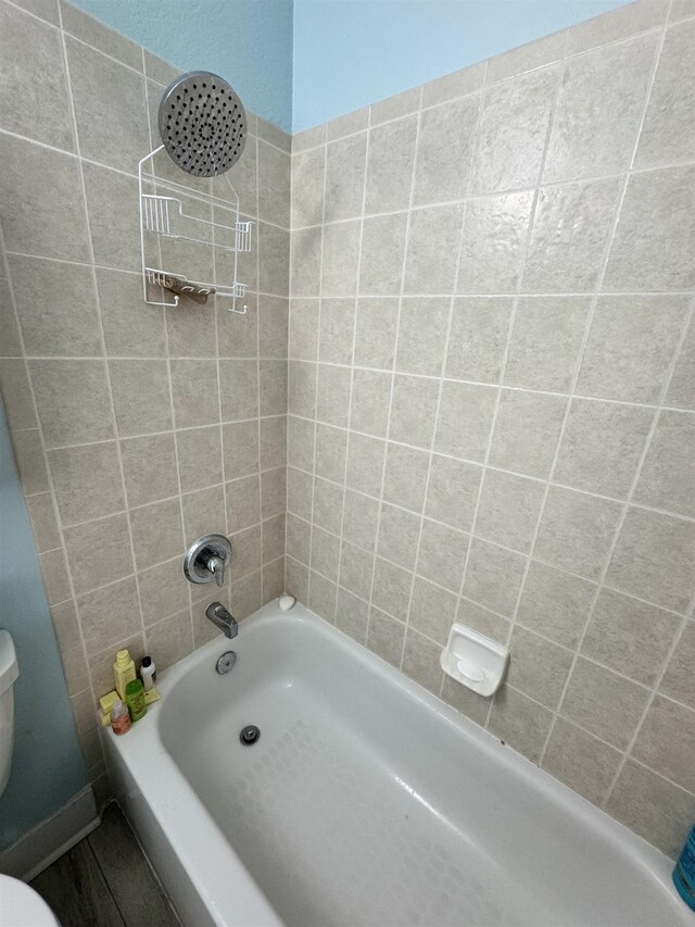 bathroom featuring toilet and tiled shower / bath combo