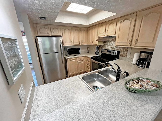 kitchen with a sink, stainless steel appliances, light brown cabinets, a textured ceiling, and light countertops