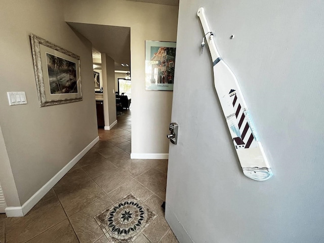 corridor with baseboards and tile patterned floors
