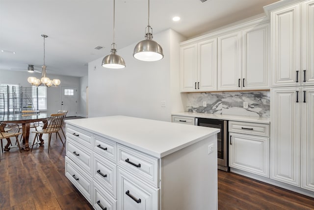 kitchen with pendant lighting, light countertops, backsplash, dark wood-type flooring, and white cabinetry