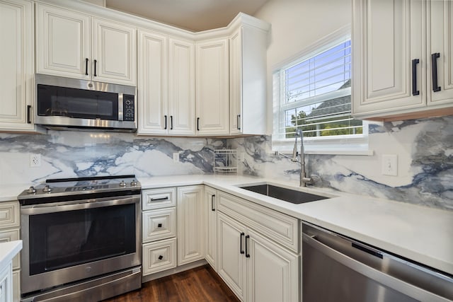 kitchen with a sink, light countertops, appliances with stainless steel finishes, backsplash, and dark wood finished floors