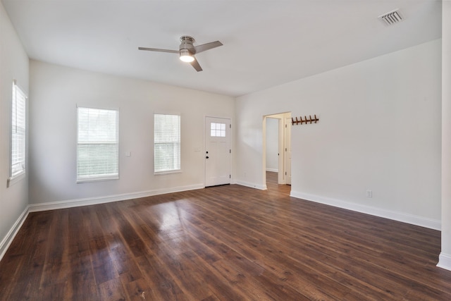 empty room with dark wood-style floors, ceiling fan, visible vents, and baseboards