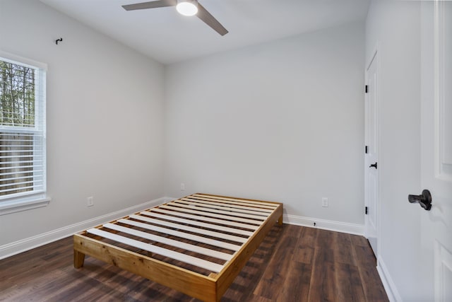 bedroom with dark wood finished floors, a ceiling fan, and baseboards