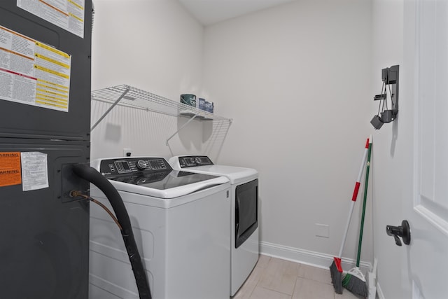 clothes washing area featuring laundry area, baseboards, and washer and dryer