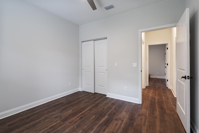 unfurnished bedroom with ceiling fan, visible vents, baseboards, a closet, and dark wood-style floors