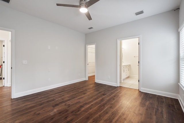 unfurnished bedroom with dark wood-style flooring, visible vents, and baseboards