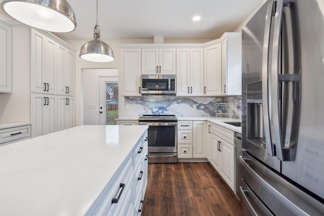 kitchen with stainless steel appliances, hanging light fixtures, decorative backsplash, and white cabinets