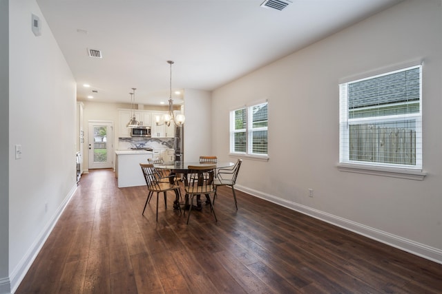 dining space featuring a chandelier, dark wood-style flooring, visible vents, and baseboards