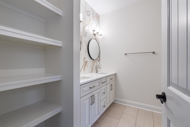 bathroom featuring tile patterned flooring, a sink, baseboards, and double vanity