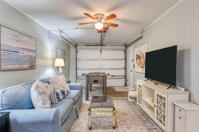 living room featuring a textured ceiling, ceiling fan, wood walls, and crown molding