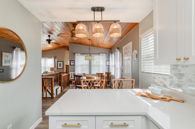 kitchen featuring light stone countertops, decorative light fixtures, vaulted ceiling, and plenty of natural light