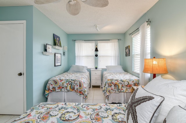 tiled bedroom featuring multiple windows, a textured ceiling, and ceiling fan