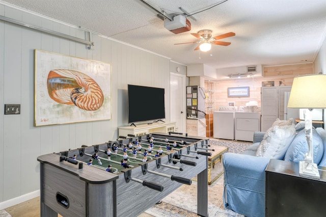 recreation room featuring wooden walls, ceiling fan, a textured ceiling, and independent washer and dryer