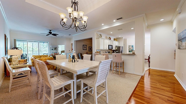 dining room featuring ornamental molding, light hardwood / wood-style flooring, and ceiling fan with notable chandelier