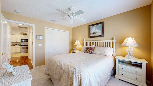 carpeted bedroom with a closet, ceiling fan, and a textured ceiling