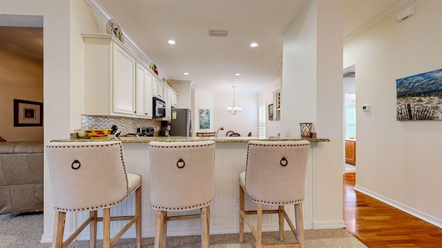 kitchen with tasteful backsplash, kitchen peninsula, a breakfast bar area, hanging light fixtures, and appliances with stainless steel finishes