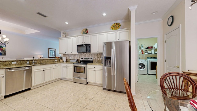 kitchen featuring appliances with stainless steel finishes, stone countertops, washer / dryer, and sink