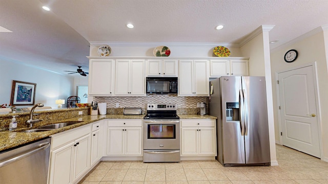 kitchen with kitchen peninsula, stainless steel appliances, white cabinets, dark stone countertops, and sink