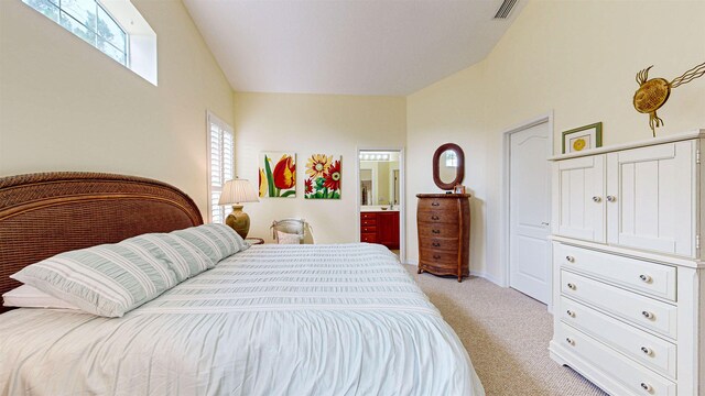 bedroom with ensuite bathroom and light colored carpet