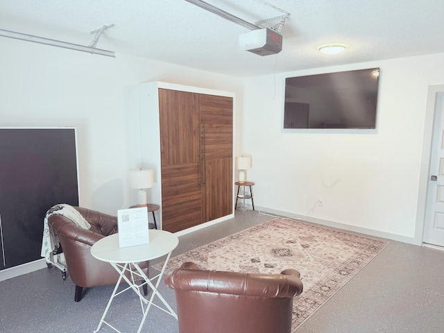 sitting room with baseboards, a garage, and a textured ceiling