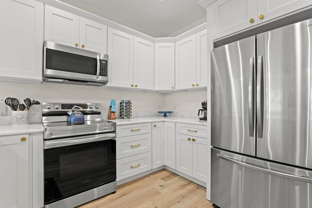 kitchen with light wood-type flooring, light countertops, appliances with stainless steel finishes, and white cabinetry