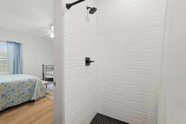 full bath featuring a tile shower, a ceiling fan, and wood finished floors