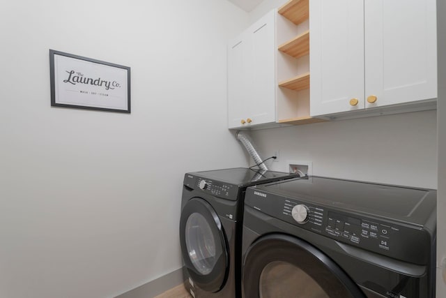 washroom featuring baseboards, washer and dryer, and cabinet space