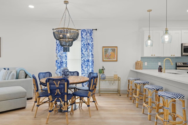 dining space featuring baseboards, light wood-style floors, a chandelier, and recessed lighting