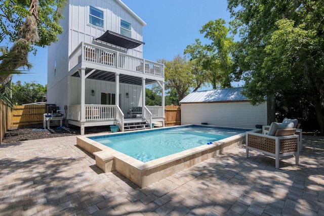 back of property with a balcony, a patio, a fenced backyard, a fenced in pool, and board and batten siding