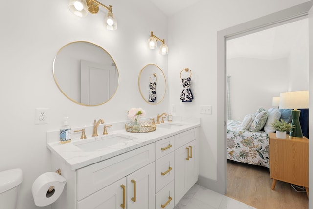 full bath featuring toilet, connected bathroom, double vanity, and a sink