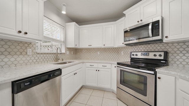 kitchen with sink, white cabinetry, stainless steel appliances, light tile patterned flooring, and decorative backsplash