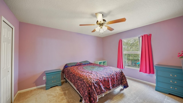 bedroom featuring ceiling fan, light colored carpet, and a textured ceiling