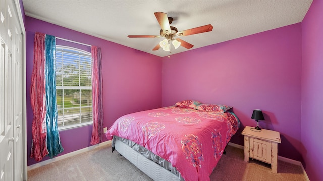 carpeted bedroom featuring ceiling fan and a textured ceiling