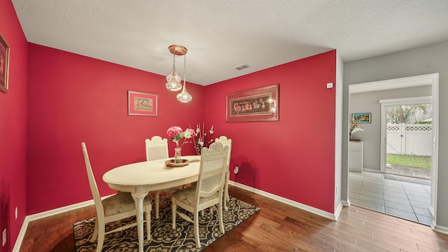 dining space featuring hardwood / wood-style floors and a textured ceiling