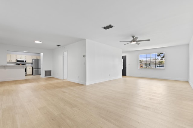 unfurnished living room featuring ceiling fan, light wood finished floors, visible vents, and baseboards