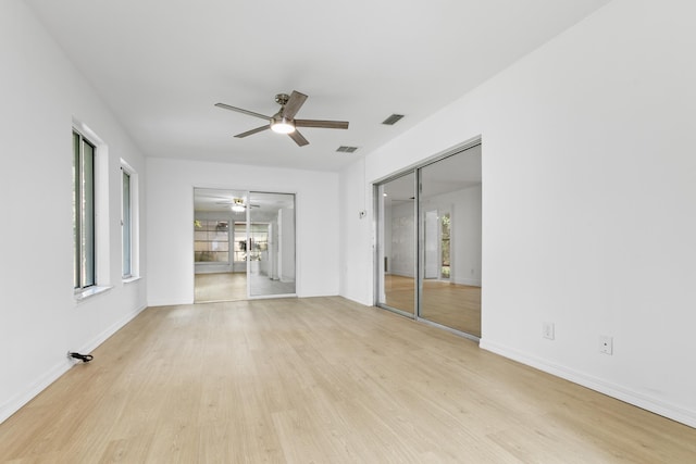 empty room with light wood-style floors, baseboards, visible vents, and a ceiling fan