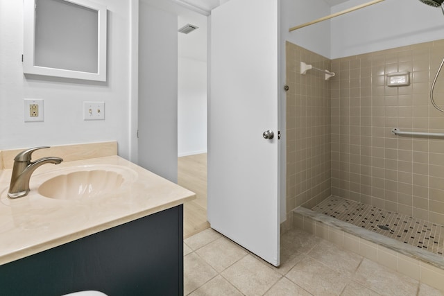 full bath with vanity, tile patterned flooring, a tile shower, and visible vents