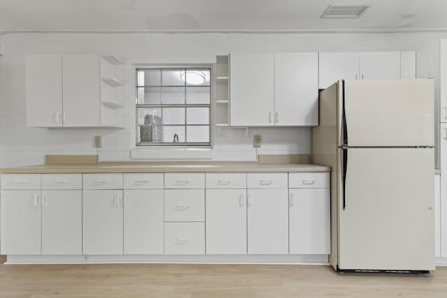 kitchen featuring visible vents, open shelves, light countertops, and freestanding refrigerator