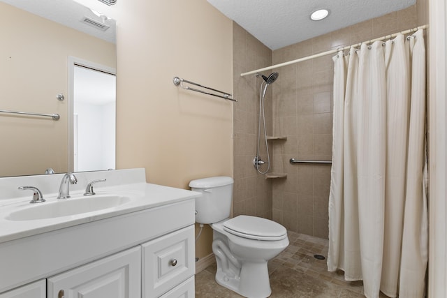 bathroom with toilet, a tile shower, vanity, a textured ceiling, and tile patterned flooring