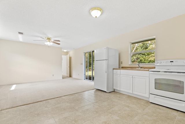 kitchen featuring light carpet, white appliances, visible vents, white cabinetry, and a sink