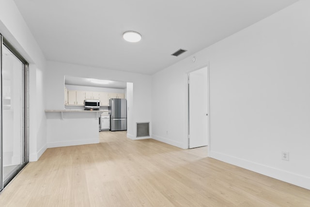 unfurnished living room with light wood finished floors, visible vents, and baseboards