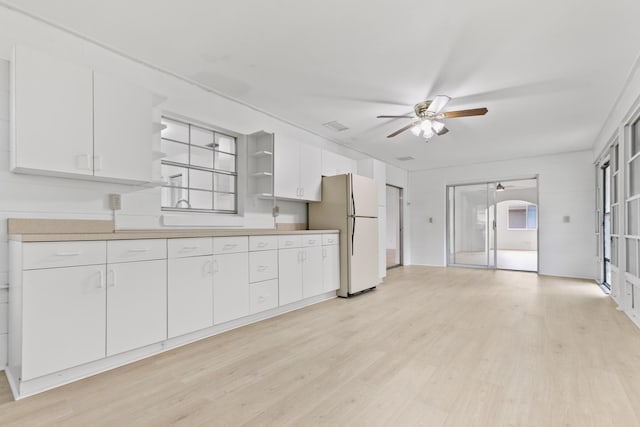 kitchen with light wood-type flooring, ceiling fan, open shelves, and freestanding refrigerator